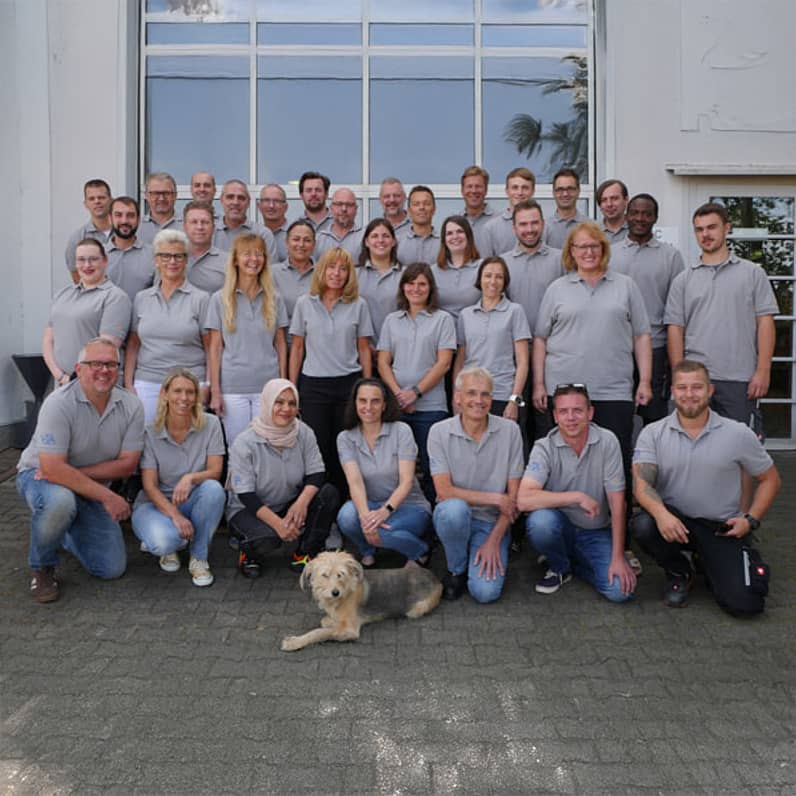 35 UIC employees in gray shirts with a dog in front of a building