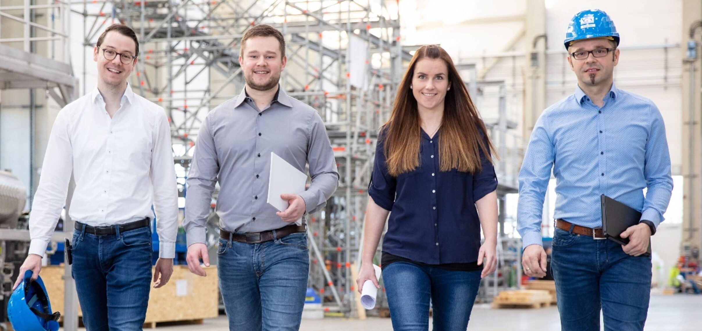 four workers smiling and walking on industrial site