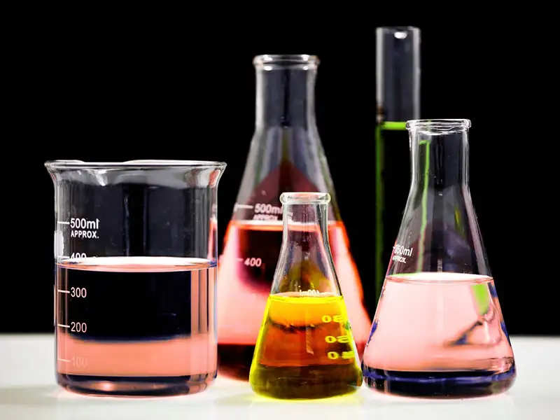 5 glass beakers with liquid in them with black background